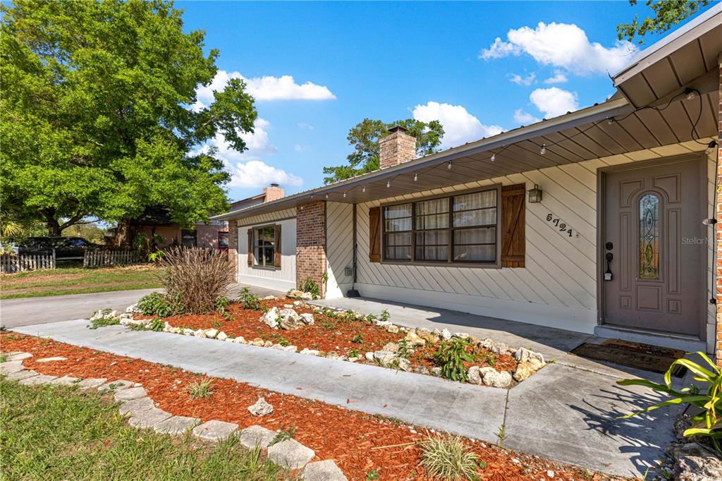 A single-story house with white diagonal siding, a brick chimney, and a front porch — 5721 SE 21ST LANE, OCALA, FL