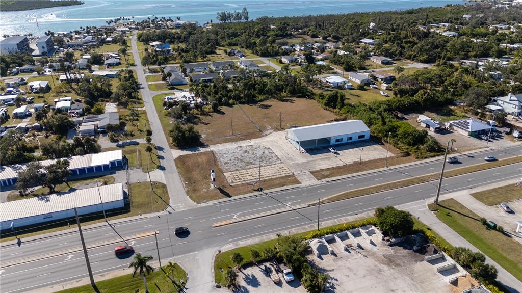 An aerial view shows a commercial building with a large parking lot along a highway — 3060 PLACIDA ROAD, ENGLEWOOD, FL