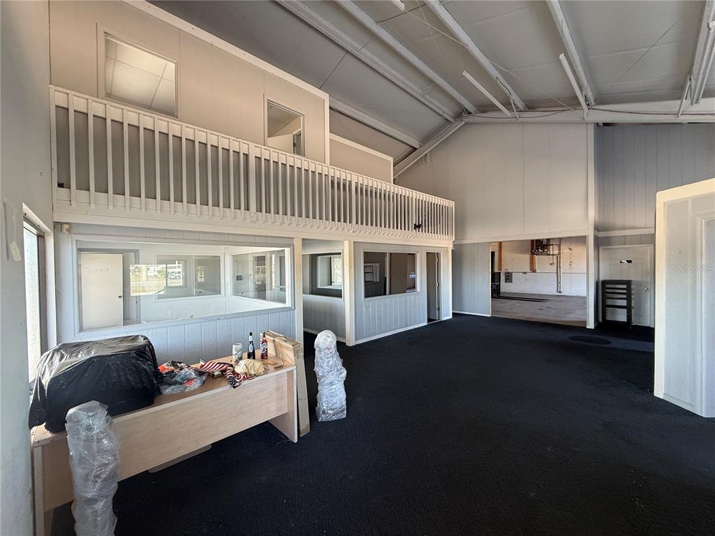 An interior view shows a large open space with black carpeting, a lofted balcony, and partitioned offices — 3060 PLACIDA ROAD, ENGLEWOOD, FL
