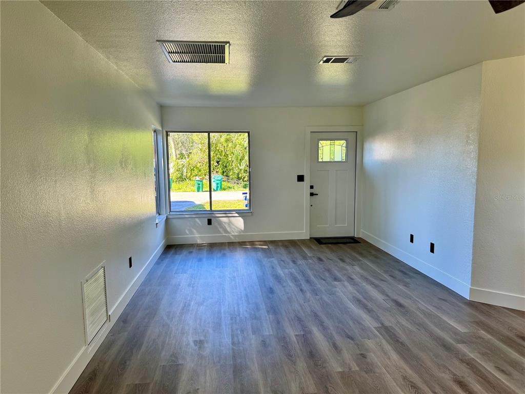 An empty room with light-colored walls, wood-look flooring, a window, and a white door — 325 CAPATOLA ST, PORT CHARLOTTE, FL