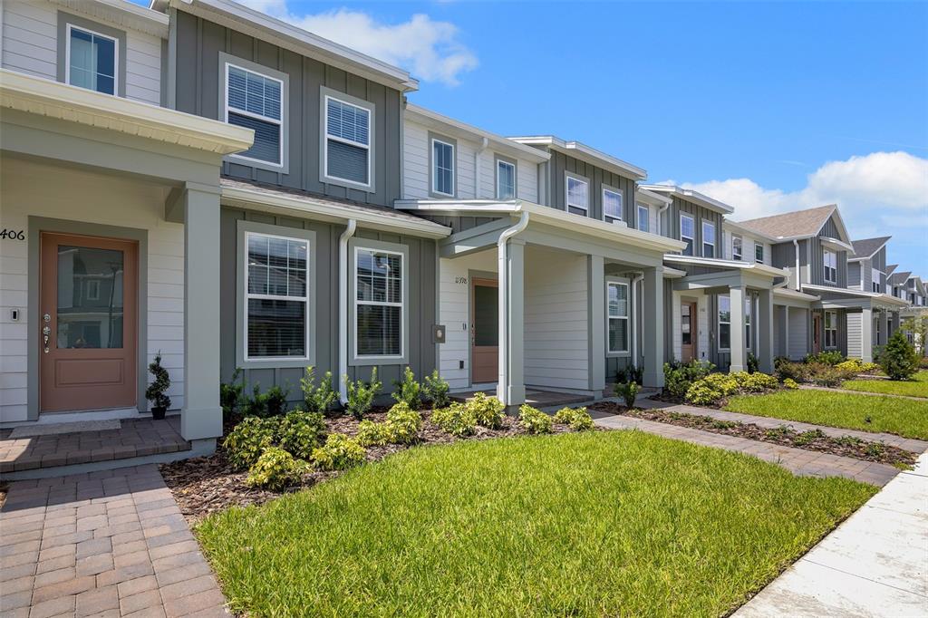 A row of modern two-story townhomes features gray and white siding with covered front porches — 11398 NONA SOUND STREET, ORLANDO, FL