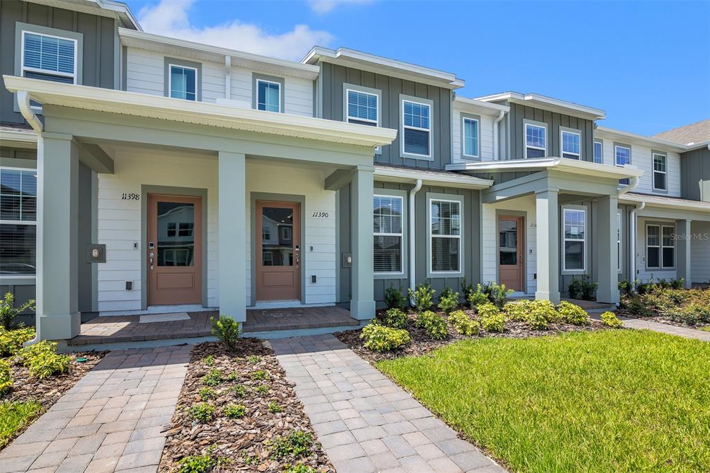 The exterior of a multi-unit townhouse complex features tan doors and gray siding — 11398 NONA SOUND STREET, ORLANDO, FL