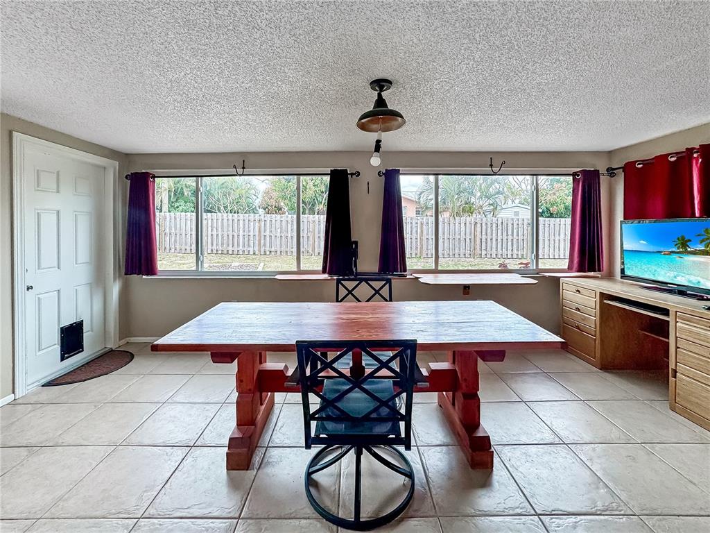 A dining room features a wooden table, tile flooring, large windows, and a built-in desk — 934 FUNDY ROAD, VENICE, FL