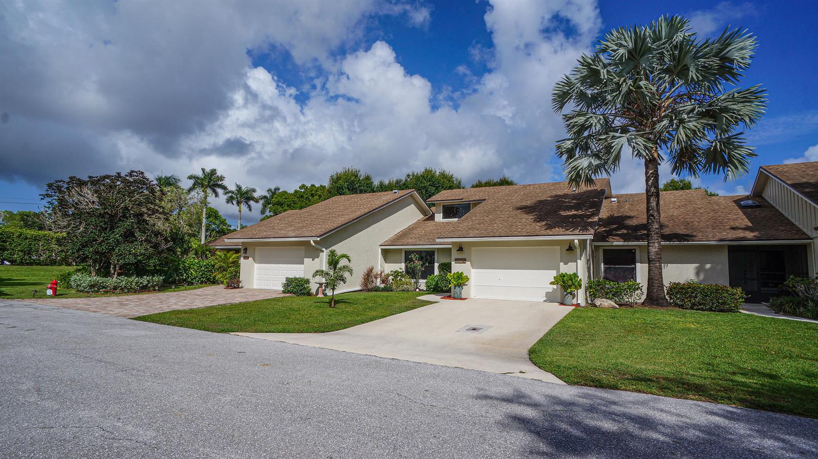 A view of two attached single-story homes with driveways, lawns, and a tall palm tree — 11894 Donlin Drive, Wellington FL 33414, WELLINGTON, FL
