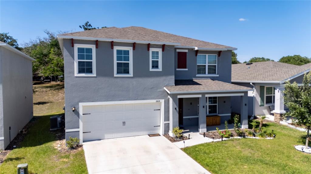 A two-story gray house with a white garage door and a covered front porch — 2824 BIG SUR ROAD, DAVENPORT, FL