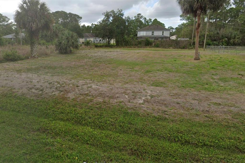 A vacant, grassy residential lot with scattered trees and neighboring houses in the background — 368 GATES STREET SW, PALM BAY, FL