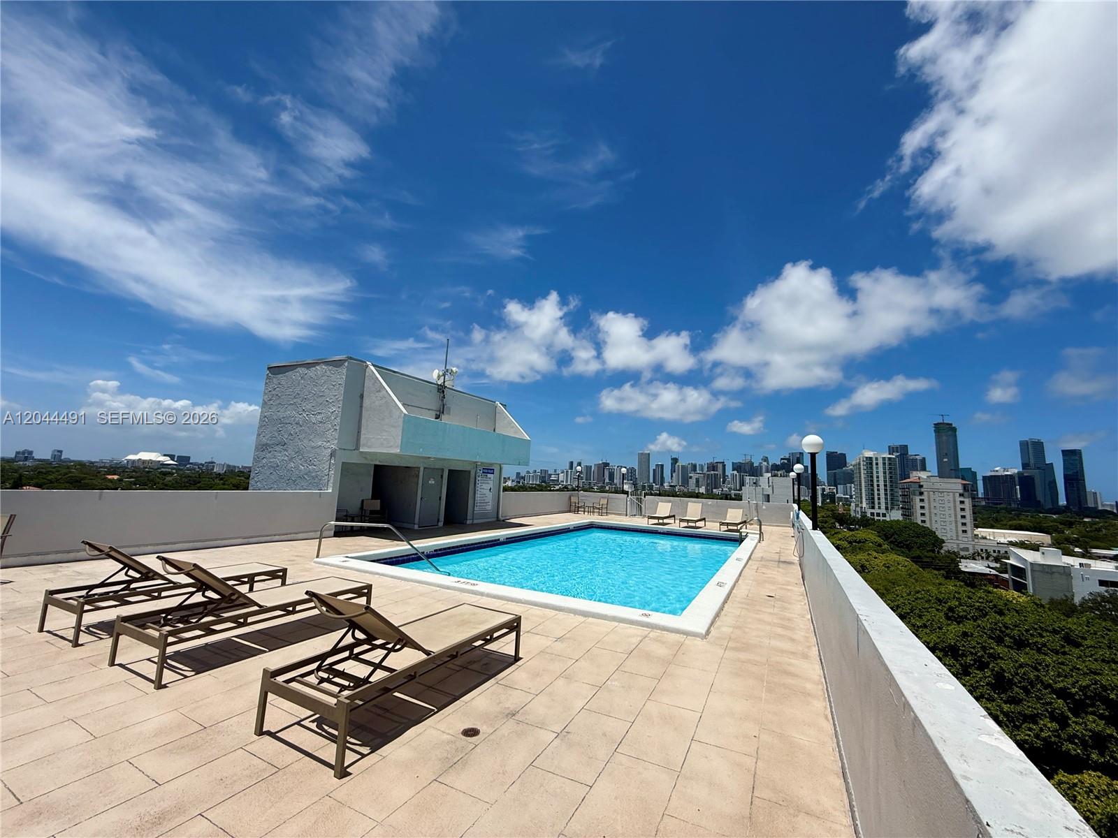 A rooftop swimming pool features lounge chairs on a tiled deck overlooking a city skyline — 2950 SW 3rd Ave # 3C, Miami FL 33129, MIAMI, FL