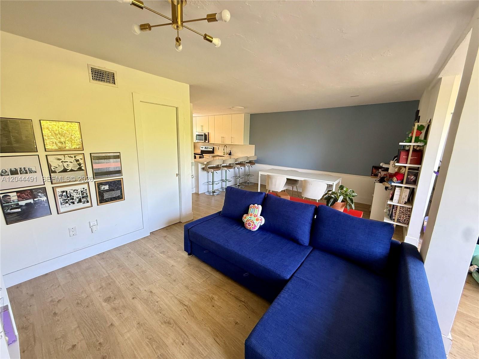 A living room with a blue sectional sofa, light wood floors, and an adjacent kitchen — 2950 SW 3rd Ave # 3C, Miami FL 33129, MIAMI, FL