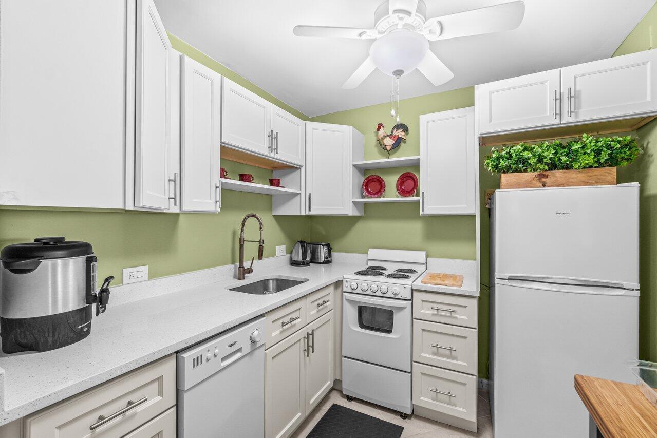 A small kitchen features white cabinets, light countertops, green walls, and a white refrigerator — 68 Suffolk B # 68, Boca Raton FL 33434, BOCA RATON, FL