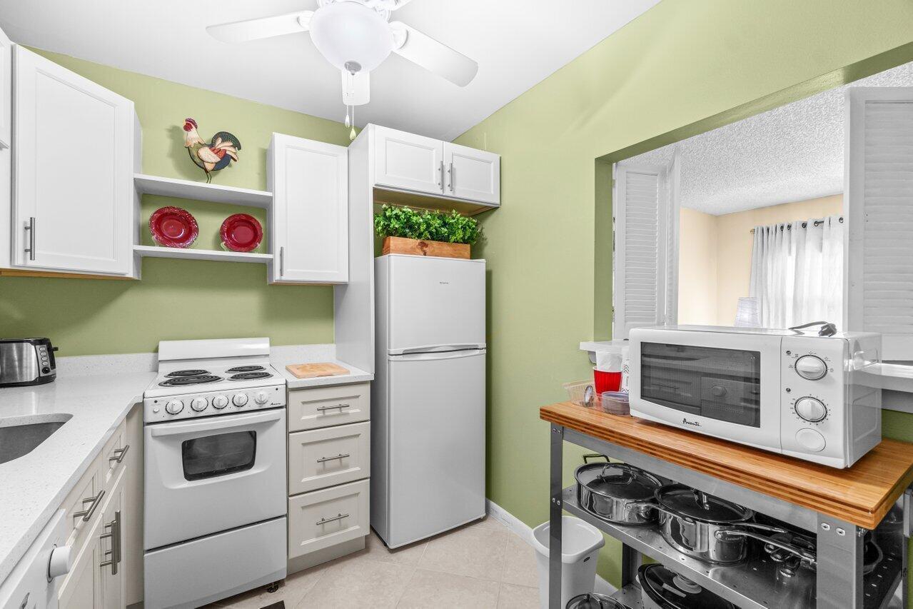A kitchen with white cabinets, a white stove, a refrigerator, and a microwave on a cart — 68 Suffolk B # 68, Boca Raton FL 33434, BOCA RATON, FL