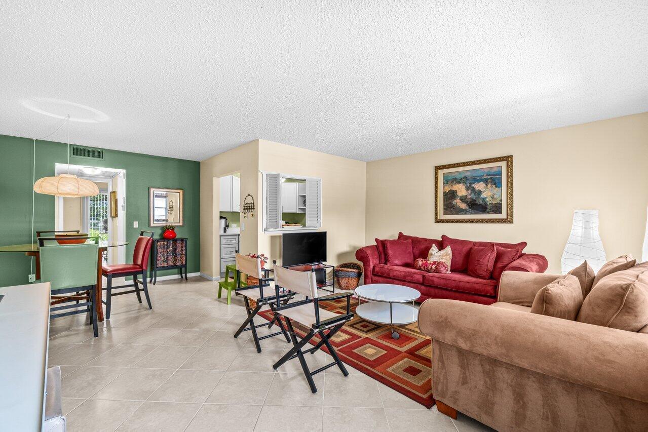 A living and dining area features tile flooring, a red sofa, and a green wall — 68 Suffolk B # 68, Boca Raton FL 33434, BOCA RATON, FL