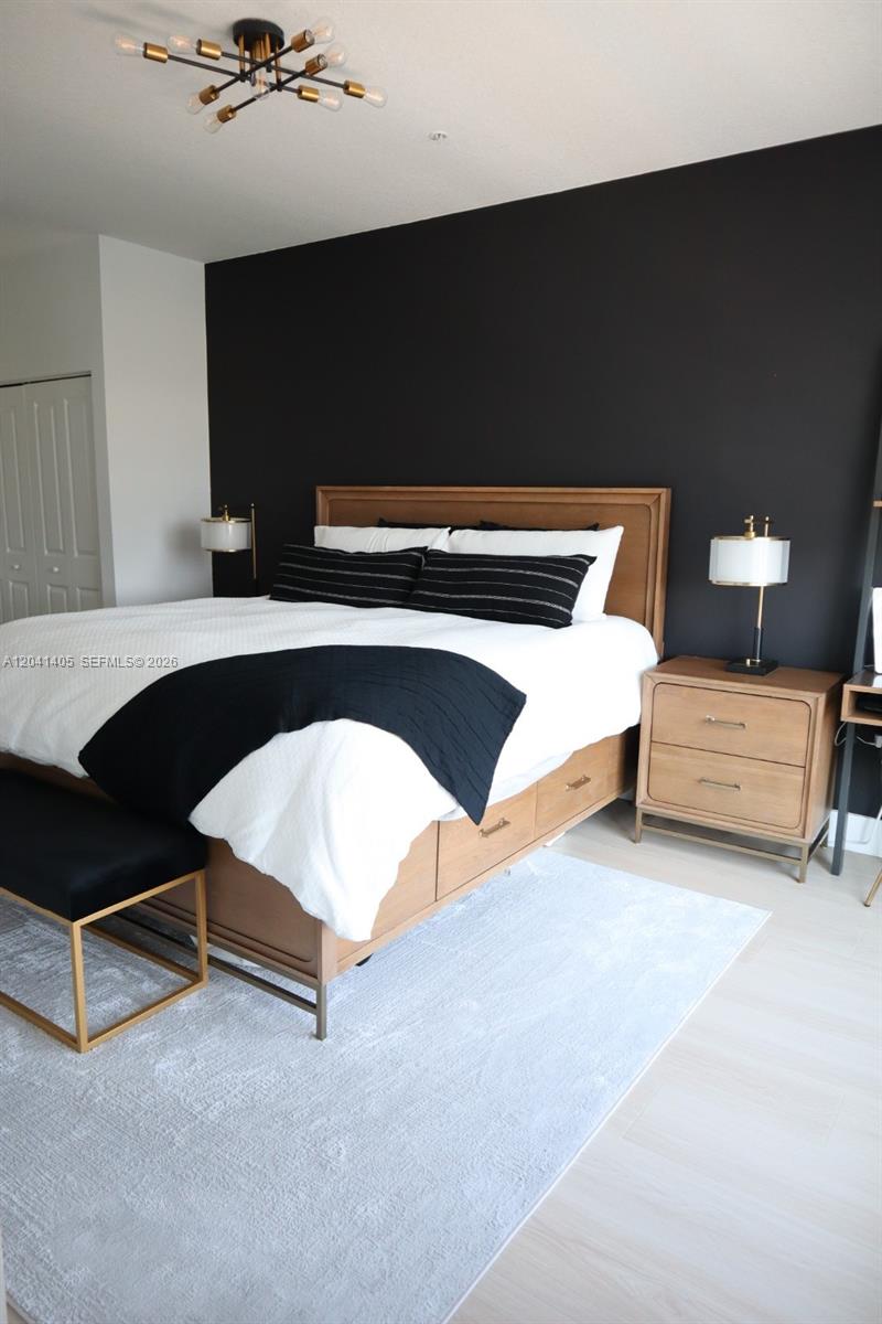 A bedroom features a bed with a wooden frame, black accent wall, and modern lighting — 8201 NW 41st St # 402, Doral FL 33166, DORAL, FL
