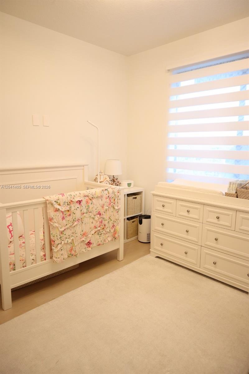 A nursery features a white crib, a matching dresser with a changing pad, and blinds — 8201 NW 41st St # 402, Doral FL 33166, DORAL, FL