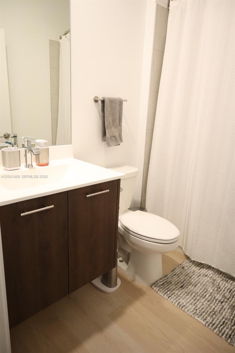 A bathroom features a dark wood vanity, a white toilet, and a shower with curtains — 8201 NW 41st St # 402, Doral FL 33166, DORAL, FL