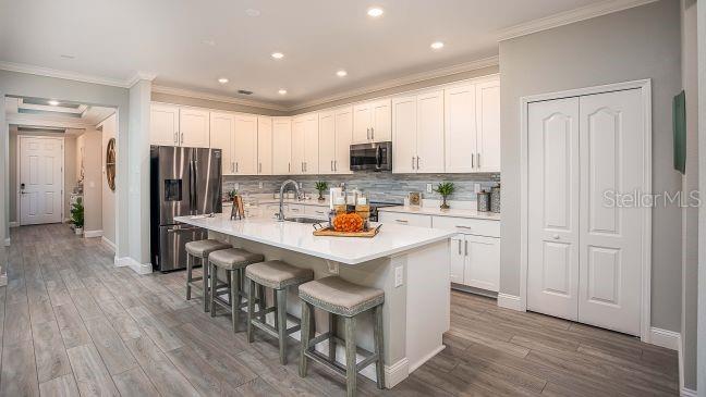 A modern kitchen features white cabinetry, a large quartz island, and stainless steel appliances — 17657 NW 169TH PLACE, ALACHUA, FL