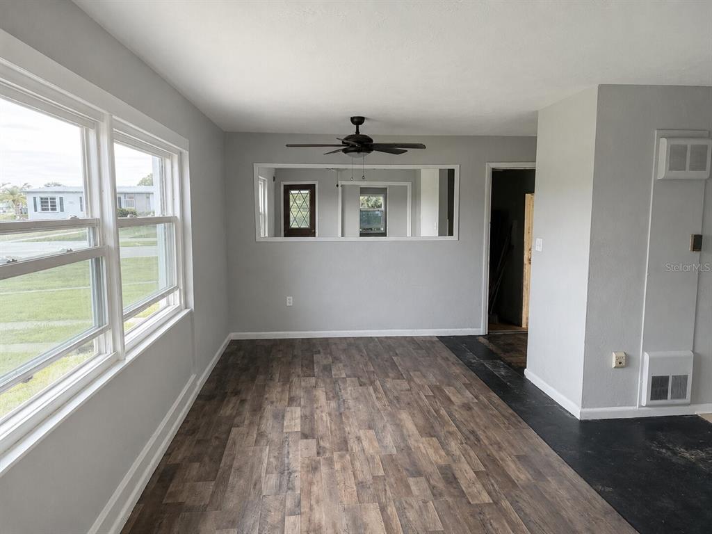 A room with gray walls, wood-look flooring, a ceiling fan, and a large wall mirror — 21098 GEPHART AVENUE, PORT CHARLOTTE, FL