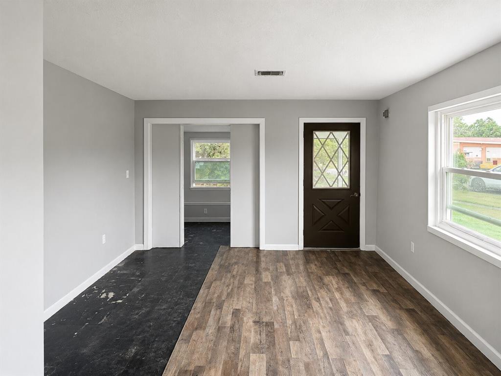 A room with gray walls, a brown door, and a mix of black and wood-look flooring — 21098 GEPHART AVENUE, PORT CHARLOTTE, FL
