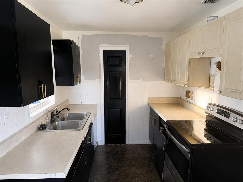 A kitchen features black and white cabinets, a double sink, and a black door — 21098 GEPHART AVENUE, PORT CHARLOTTE, FL