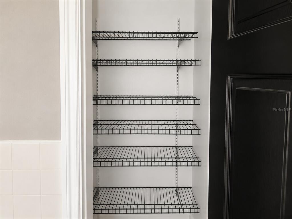 A narrow closet features six black wire shelves mounted on white walls — 21098 GEPHART AVENUE, PORT CHARLOTTE, FL
