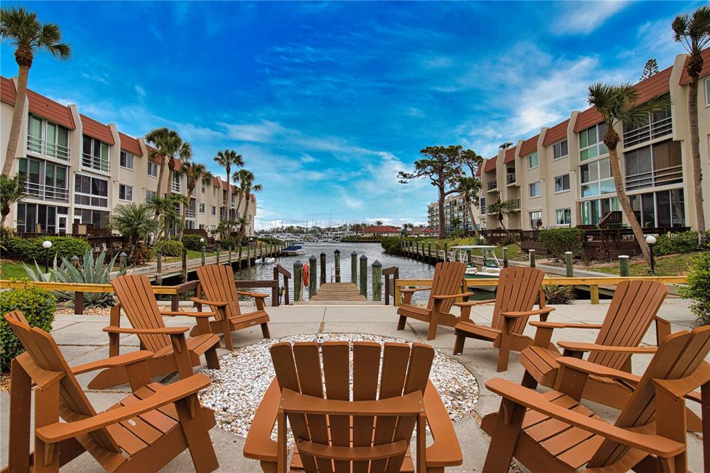 A patio with several wooden Adirondack chairs overlooks a narrow canal lined with apartment buildings — 240 SANTA MARIA STREET UNIT 225, VENICE, FL