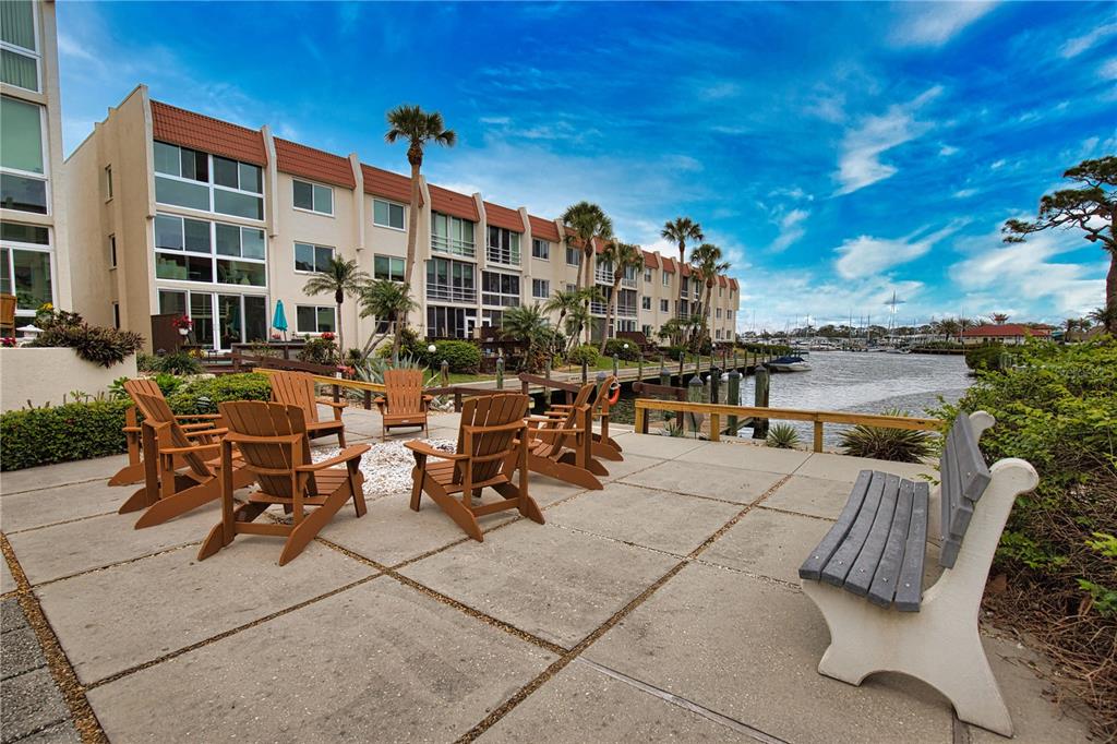 A concrete patio with Adirondack chairs and a bench overlooks a canal and apartment building — 240 SANTA MARIA STREET UNIT 225, VENICE, FL