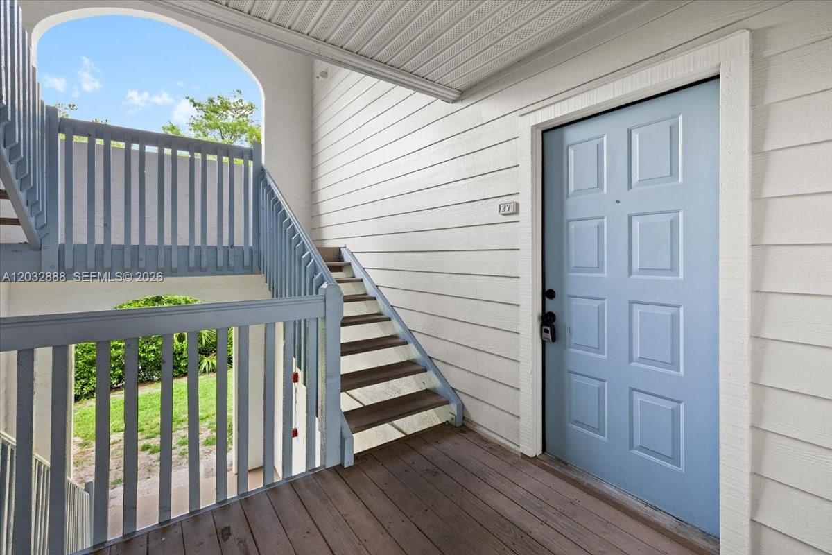A light blue front door sits on a wooden porch next to an outdoor staircase — 2303 N Congress Ave # 27, Boynton Beach FL 33426, BOYNTON BEACH, FL