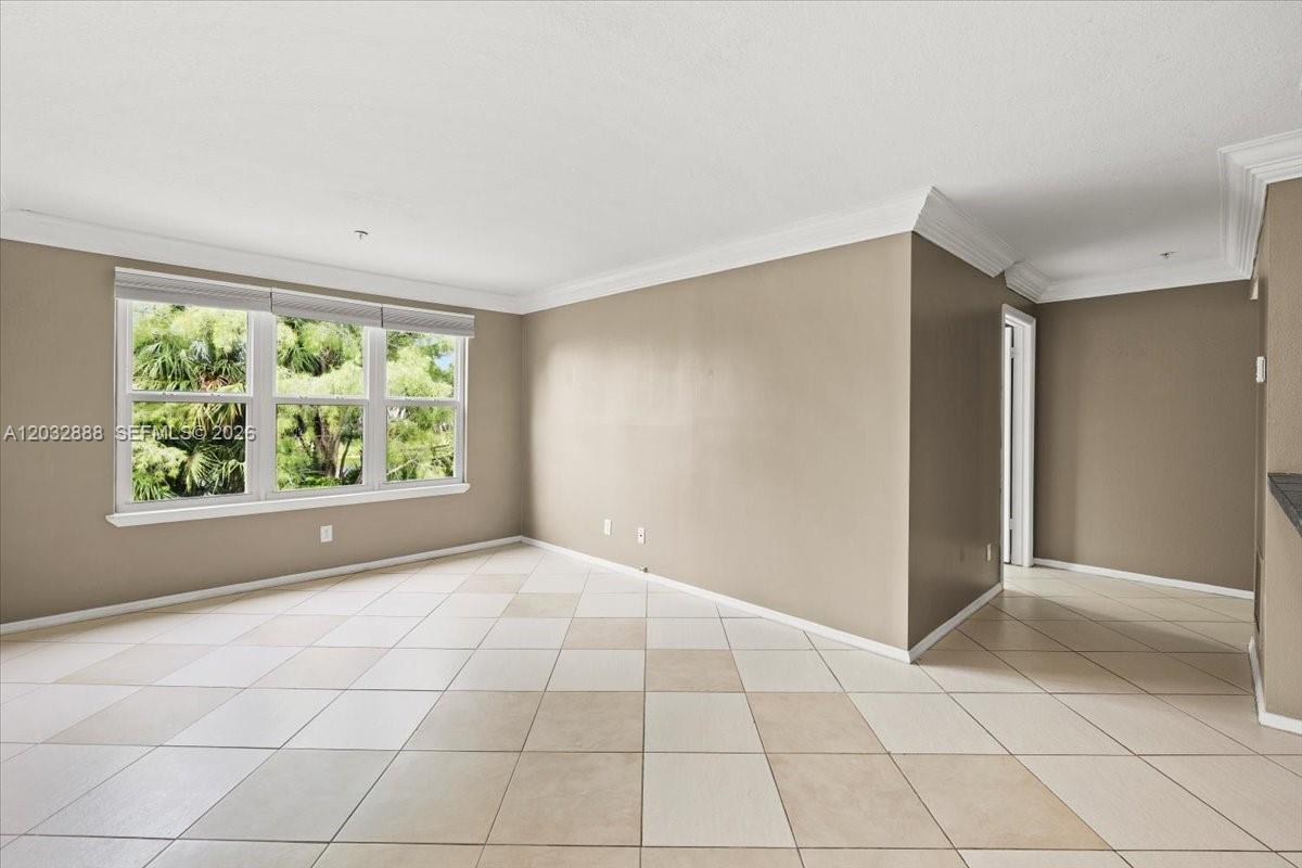 An empty room features beige walls, crown molding, and light-colored square floor tiles — 2303 N Congress Ave # 27, Boynton Beach FL 33426, BOYNTON BEACH, FL