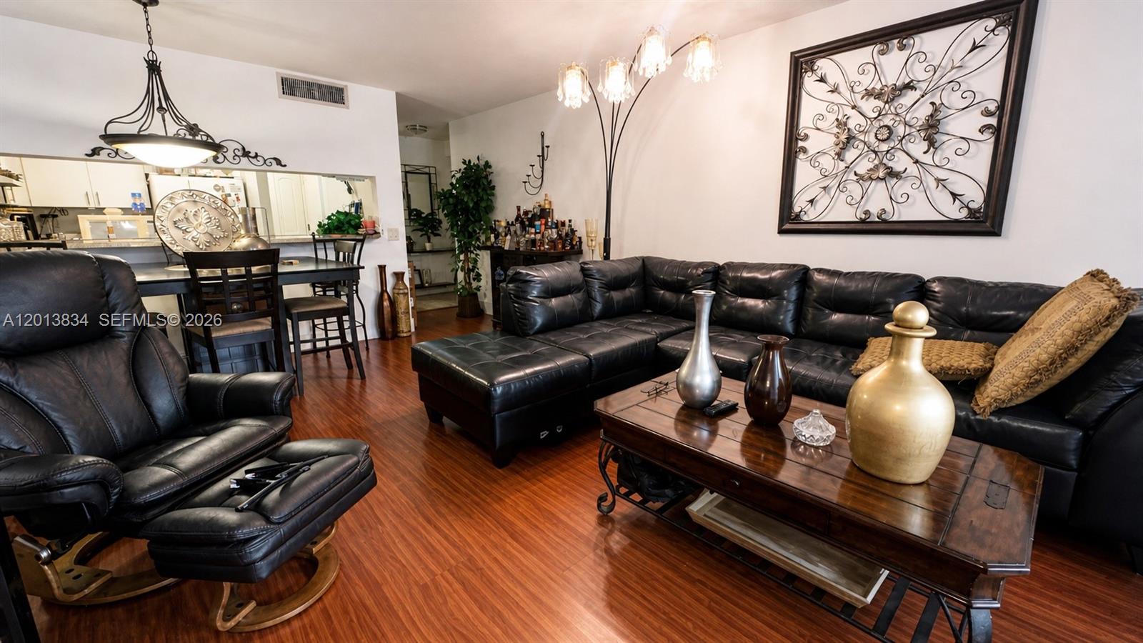 A living room features a black leather sectional, a matching recliner, and dark wood flooring — 460 S Park Rd # 109, Hollywood FL 33021, HOLLYWOOD, FL