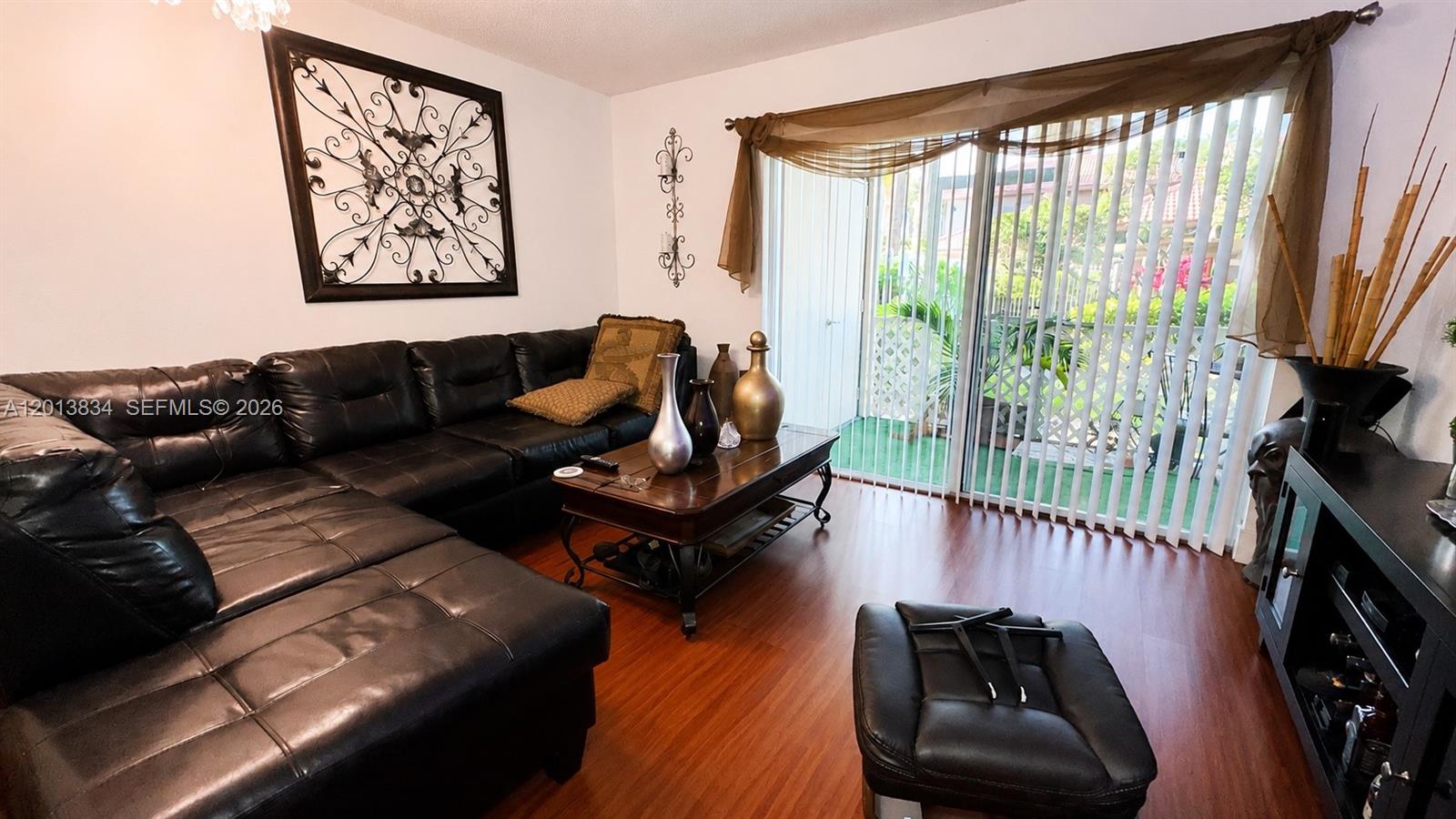 A living room features a black sectional sofa, a wooden coffee table, and sliding glass doors — 460 S Park Rd # 109, Hollywood FL 33021, HOLLYWOOD, FL