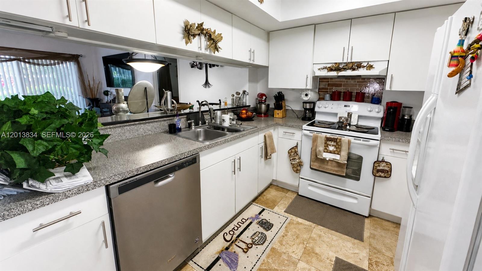 A kitchen features white cabinetry, stainless steel appliances, a tiled backsplash, and granite countertops — 460 S Park Rd # 109, Hollywood FL 33021, HOLLYWOOD, FL