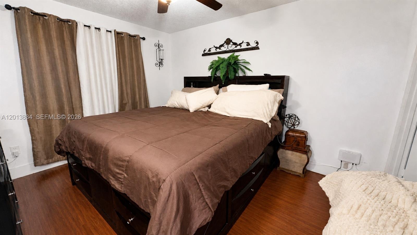A bedroom features a dark wood storage bed, brown curtains, and wood-look flooring — 460 S Park Rd # 109, Hollywood FL 33021, HOLLYWOOD, FL