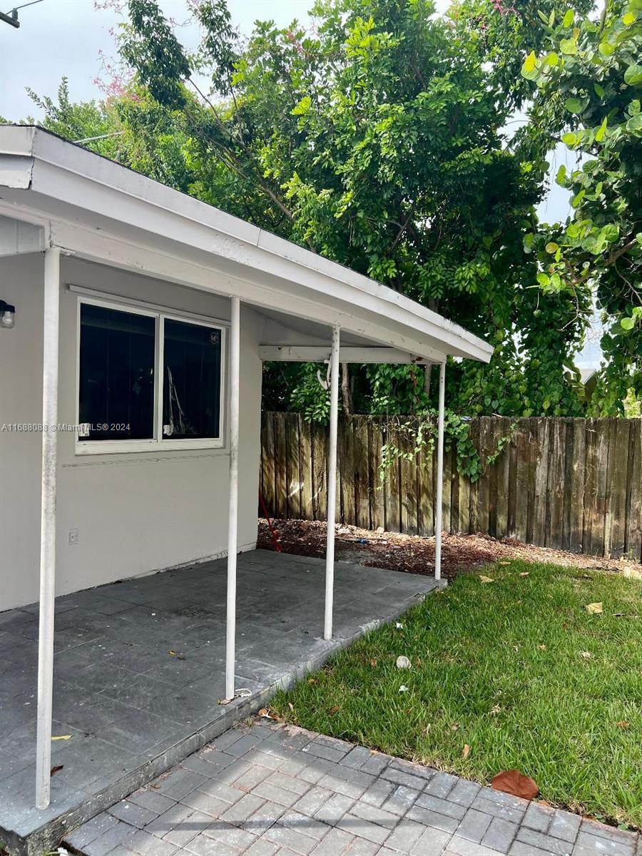 A covered patio with a concrete floor and white support posts sits beside a house — 2419 Lincoln St # 23B, Hollywood FL 33020, HOLLYWOOD, FL