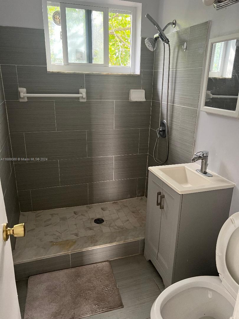 A small bathroom features a walk-in shower with gray tile walls and a pedestal sink — 2419 Lincoln St # 23B, Hollywood FL 33020, HOLLYWOOD, FL