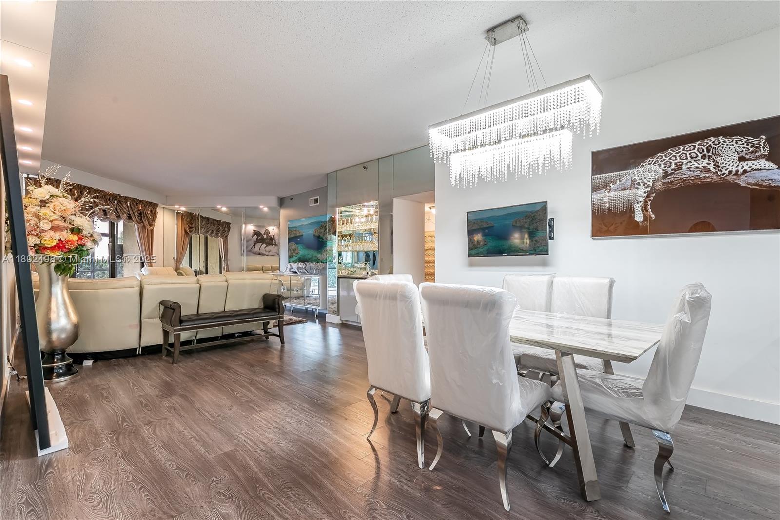 A dining area with a crystal chandelier and a living room with mirrored walls — 7300 Radice Ct # 109, Lauderhill FL 33319, LAUDERHILL, FL