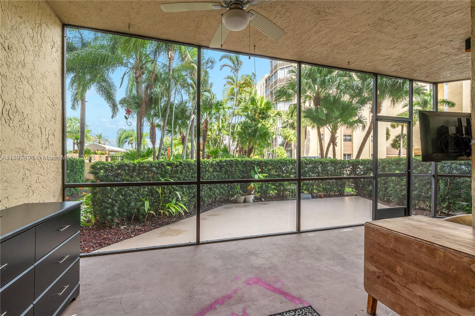 A screened-in patio features a concrete floor, a ceiling fan, and views of palm trees — 7300 Radice Ct # 109, Lauderhill FL 33319, LAUDERHILL, FL