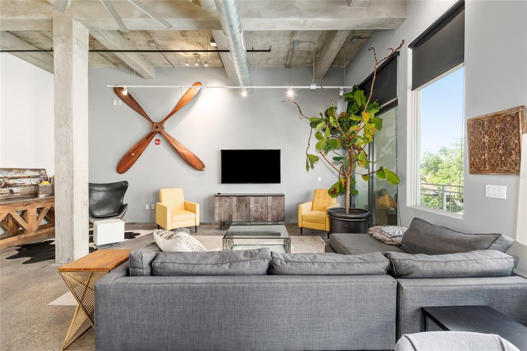 A living room features a large wooden propeller on the wall, yellow chairs, and concrete ceilings — 302 SE BROADWAY STREET UNIT 330, OCALA, FL