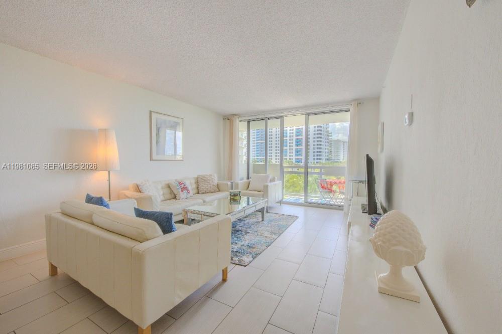 A bright living room features white tile floors, a white sofa set, and balcony access — 1500 Bay Rd # 528S, Miami Beach FL 33139, MIAMI BEACH, FL