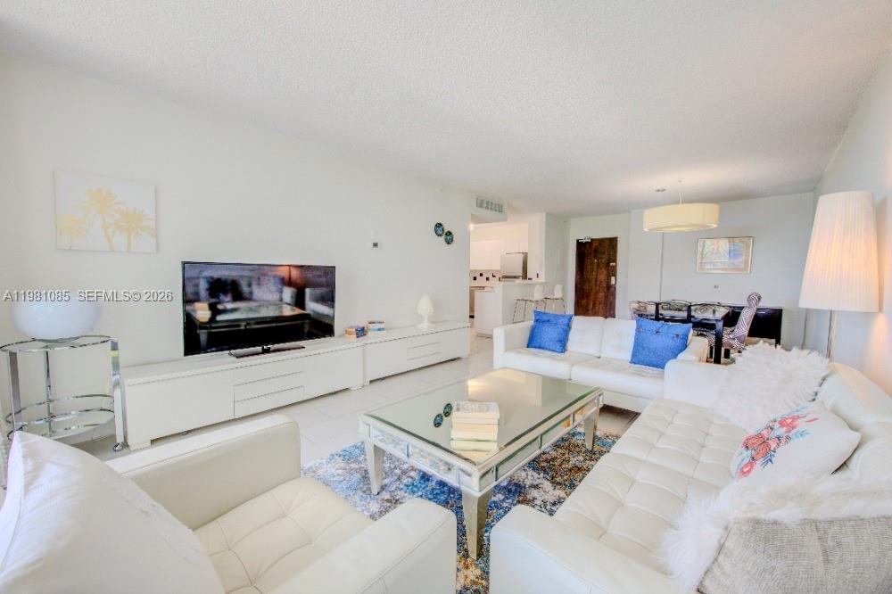 A bright living room features white leather sofas, a glass coffee table, and white cabinetry — 1500 Bay Rd # 528S, Miami Beach FL 33139, MIAMI BEACH, FL