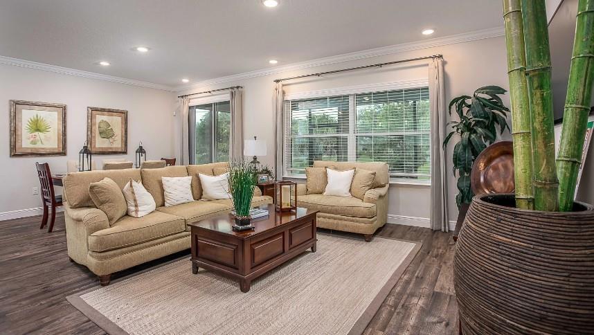 A living room features a tan sofa, matching armchair, wooden coffee table, and bamboo plant — 7726 105th Avenue, Vero Beach FL 32967, VERO BEACH, FL