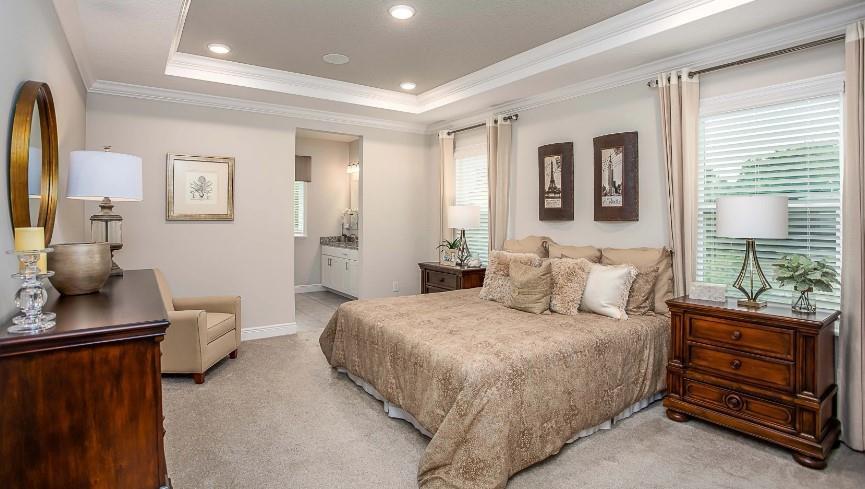 A bedroom features a tray ceiling, carpeted flooring, a king bed, and a wooden dresser — 7726 105th Avenue, Vero Beach FL 32967, VERO BEACH, FL