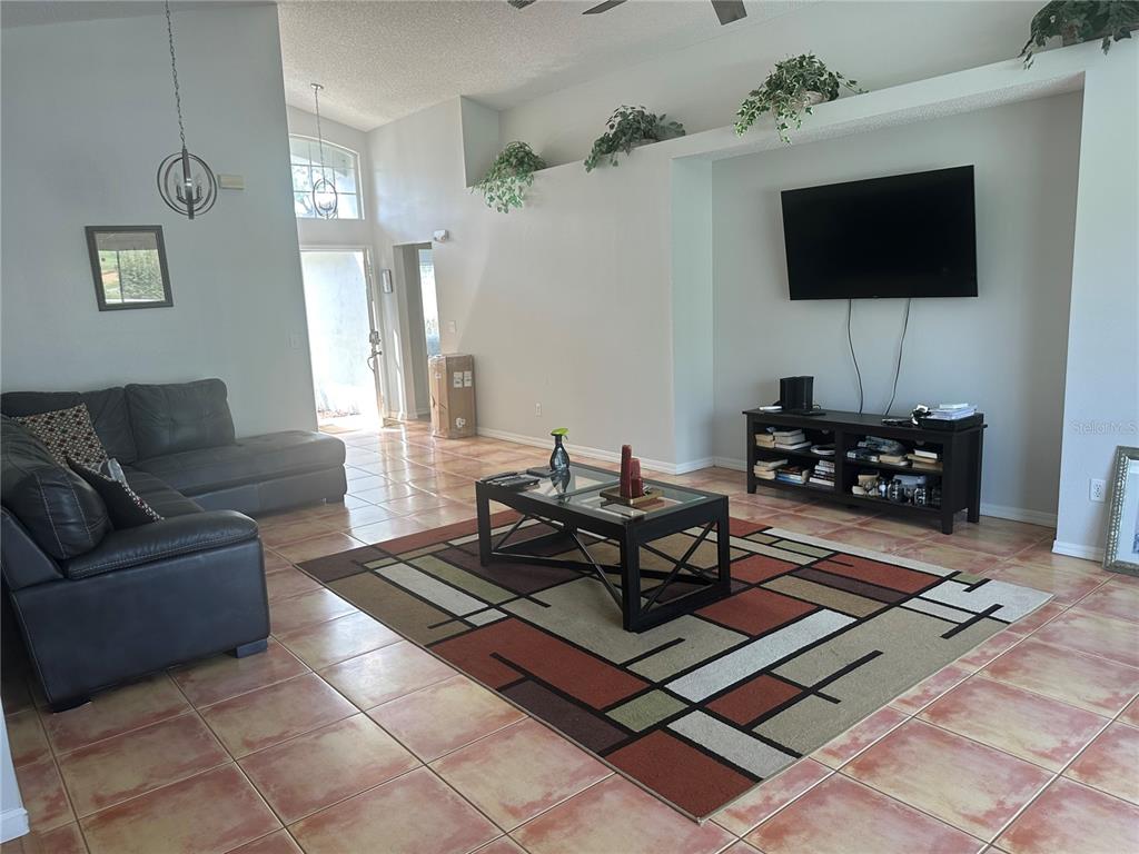 A living room features tile flooring, a leather sectional, a coffee table, and a television — 2004 HEMINGWAY AVENUE, HAINES CITY, FL