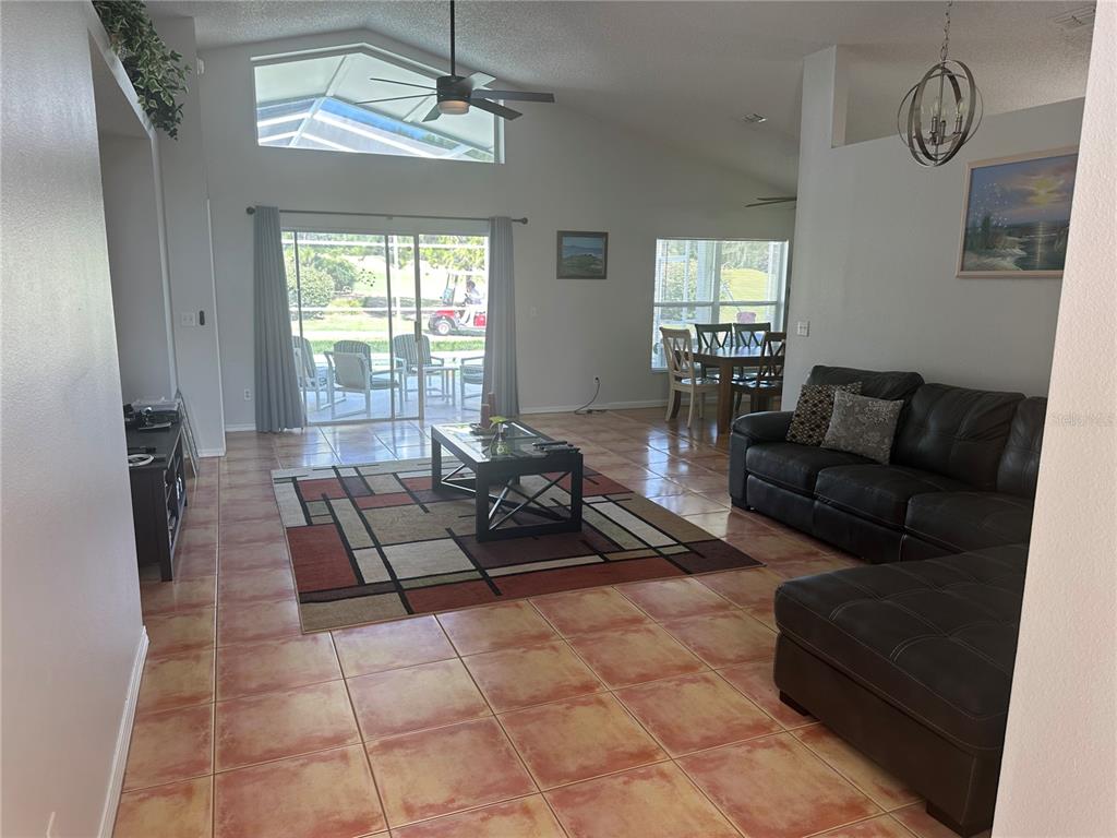 A living room with tile floors, a sectional sofa, and sliding doors leading to a patio — 2004 HEMINGWAY AVENUE, HAINES CITY, FL