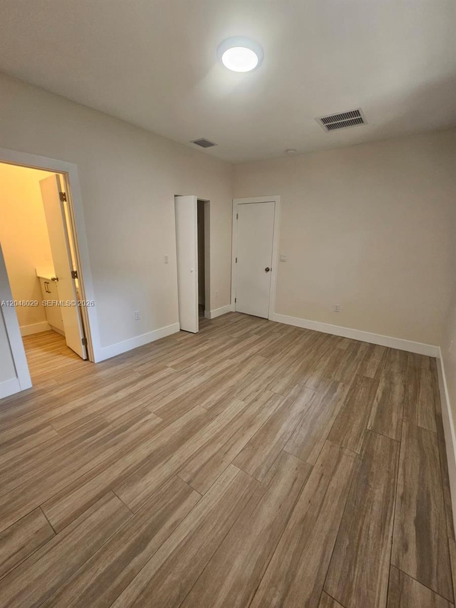 An empty bedroom features light-colored walls, wood-look tile flooring, and two closed white doors — 5428 NW 3rd Ave # B, Miami FL 33127, MIAMI, FL