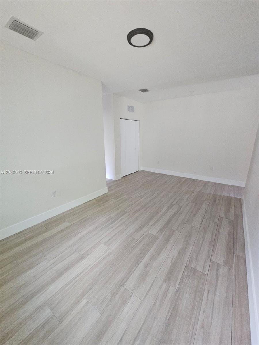 This empty room features white walls, light wood-look tile flooring, and a ceiling light fixture — 5428 NW 3rd Ave # B, Miami FL 33127, MIAMI, FL