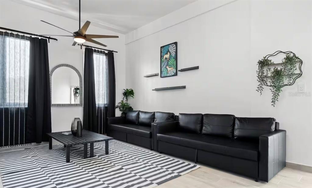 A living room features black leather sofas, a striped rug, and black curtains — 250 CALLE DEL PARQUE UNIT 3B, SAN JUAN, PR