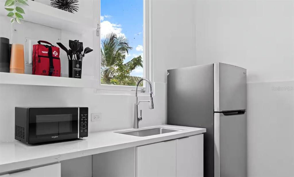A kitchen features white countertops, a stainless steel sink, a microwave, and a refrigerator — 250 CALLE DEL PARQUE UNIT 3B, SAN JUAN, PR