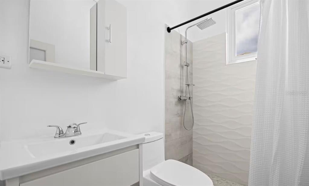A modern bathroom features a white vanity, a toilet, and a tiled walk-in shower — 250 CALLE DEL PARQUE UNIT 3B, SAN JUAN, PR