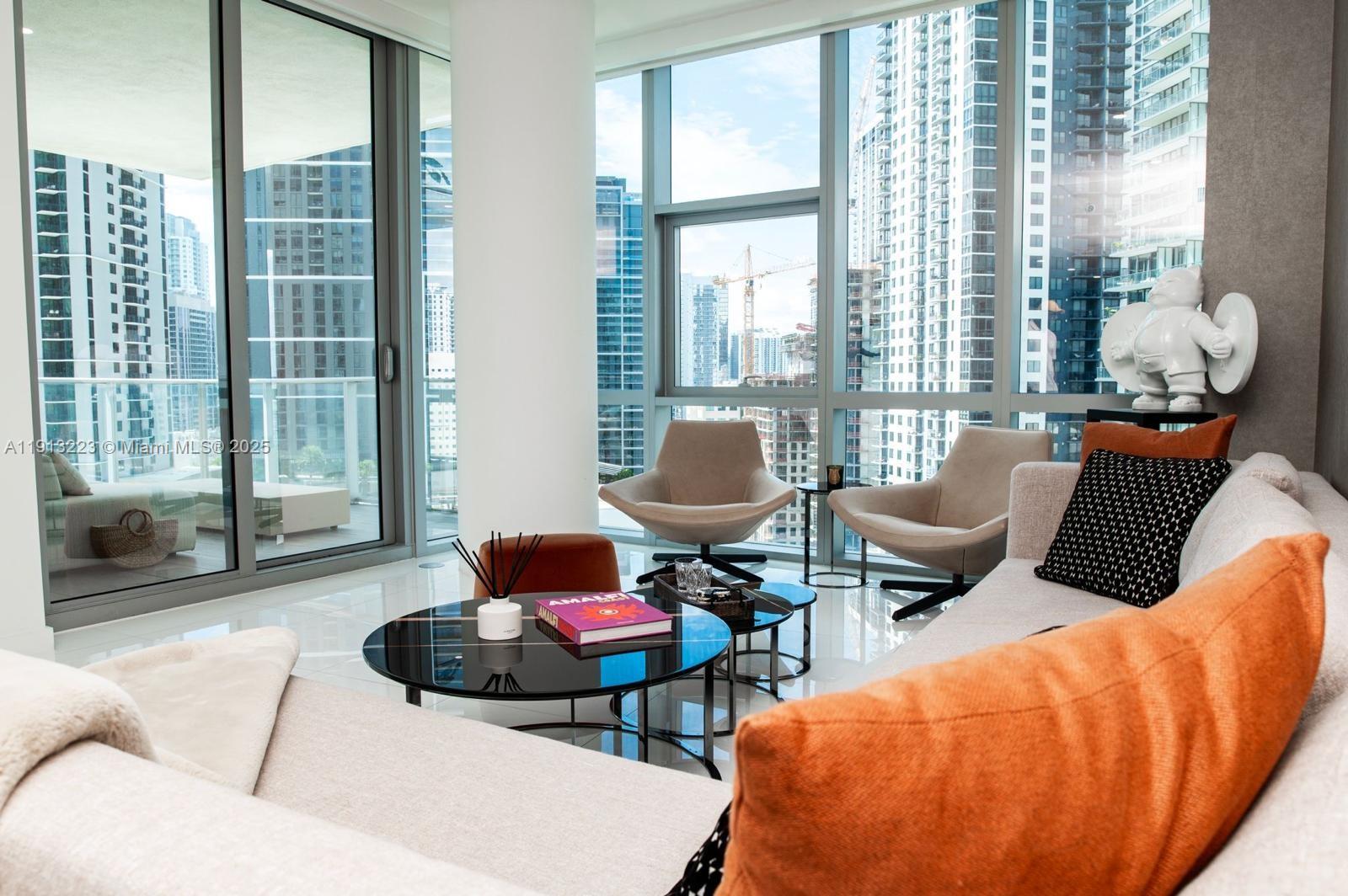 A modern living room features floor-to-ceiling windows with city views, a sectional sofa, and chairs — 851 NE 1st Ave # 1811, Miami FL 33132, MIAMI, FL
