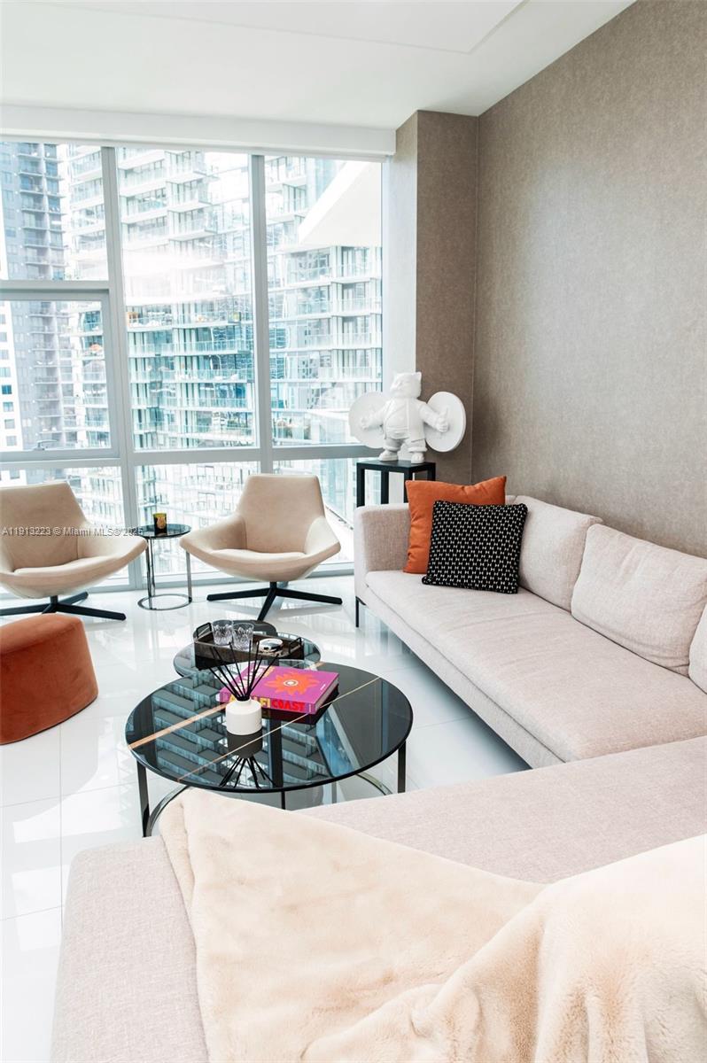 A modern living room features a light-colored sofa, two accent chairs, and floor-to-ceiling windows — 851 NE 1st Ave # 1811, Miami FL 33132, MIAMI, FL