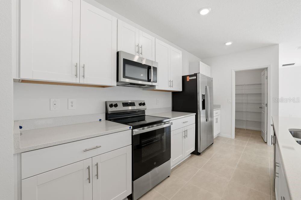 A kitchen features white cabinets, stainless steel appliances, and light-colored countertops — 13673 TROPICAL BREEZE WAY, HUDSON, FL
